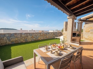 An outdoor dining area with a stone wall, a grassy lawn, and a view of the sea. - Click Sardegna Villa SeaSky – Sea View with Garde (Alghero)