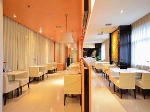 Un restaurant moderne avec un long comptoir, des chaises blanches et des luminaires suspendus.