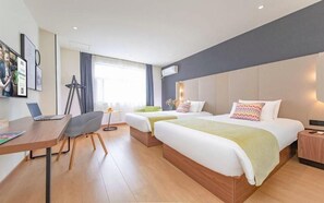 A hotel room with two beds, a desk with a laptop, a chair, and a window with curtains. - Campanile Hotel (Wuhan)