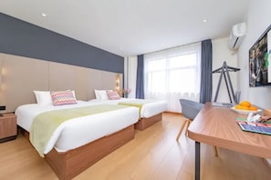 A hotel room with two beds, a desk with a chair, a window with curtains, and a wall-mounted air conditioner. - Campanile Hotel (Wuhan)