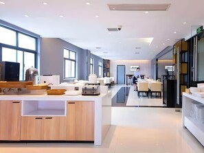 Une cuisine moderne dotée d’un îlot central, de grandes fenêtres et d’un coin repas avec des tables et des chaises.