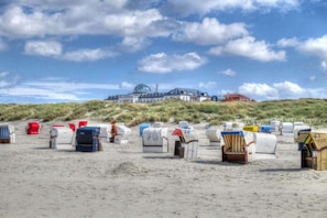 Een strand met strandstoelen en een groot gebouw op de achtergrond.