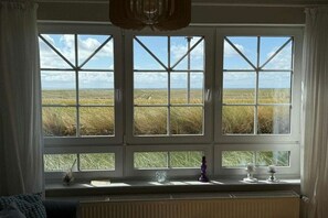 A room with a large window overlooking a grassy field. - Holiday apartment Juister Gezeiten (Juist)