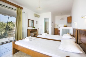 A hotel room with two beds, a balcony, a bathroom, and a kitchenette. - Saoulas Studios (Kefalonia)