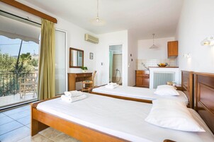 Habitación de hotel con dos camas, balcón, baño y kitchenette.
