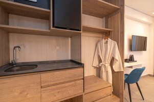 Un baño moderno con tocador de madera, lavamanos y una bata colgada en un perchero.