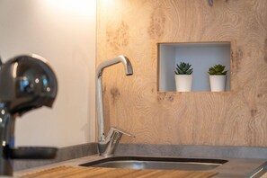 Una cocina moderna con un lavamanos empotrado, un grifo de acero inoxidable y un protector contra salpicaduras de madera.