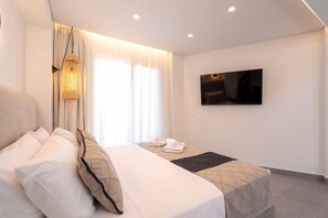Habitación de hotel con cama, televisión de pantalla plana montada en la pared y ventana con cortinas.
