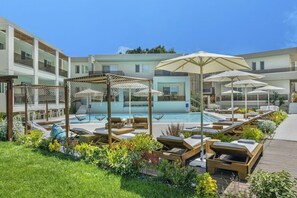 Zona junto a la piscina con sillones de playa, sombrillas y una terraza de madera.