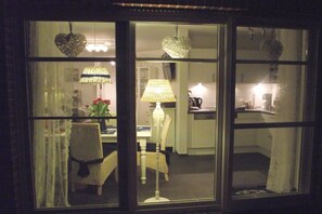 A room with a dining table, chairs, a lamp, and kitchen cabinets. - Holiday apartment with 1 bedroom (Norddeich)