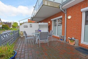 Eine Terrasse mit Tisch und Stühlen, einem Blumentopf und einer Ziegelwand.