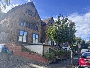 A two-story residential building with a brick facade, a visible balcony on the second floor, and a tree in front. - Bright Top Floor Flat with Balcony in Purley (London)