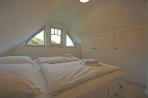 Ein Schlafzimmer mit zwei Betten, einem Fenster und einem Kleiderschrank.