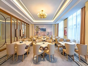 A modern dining area with round tables and chairs, a chandelier, and a cityscape mural on the wall. - Vienna Hotel Shanghai Songjiang Film & TV Park (Shanghai)