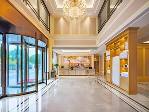 A hotel lobby with a reception desk, a chandelier, and a view through the glass doors. - Vienna Hotel Shanghai Songjiang Film & TV Park (Shanghai)