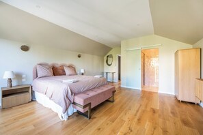 Quarto com cama, mesas de cabeceira, um banco, guarda-roupa e espelho.
