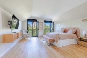 A bedroom with a bed, a TV, a bench, and a view of the outside. - Beautiful house near Paris, with a large garden and a branch of the Marne River. (Joinville Le Pont)