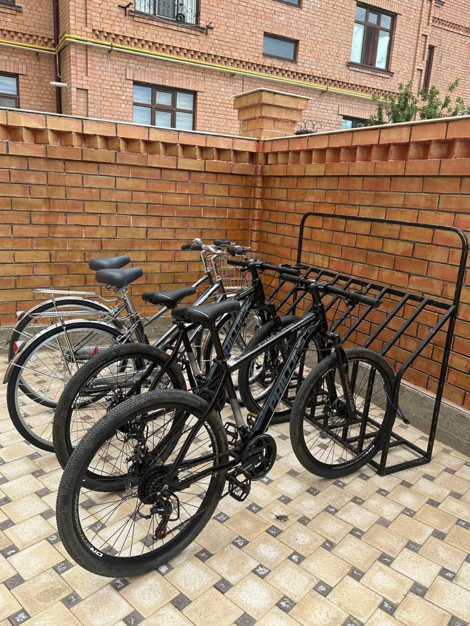 Bicycles parked in a designated bike rack area with a brick wall and tiled floor.