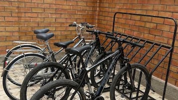 Bicycles parked in a designated bike rack area with a brick wall and tiled floor.