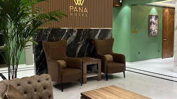 A lobby with a reception desk, seating area, and a green wall.