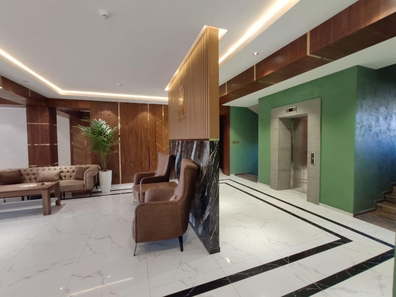 A lobby with a reception desk, seating area, and an elevator.