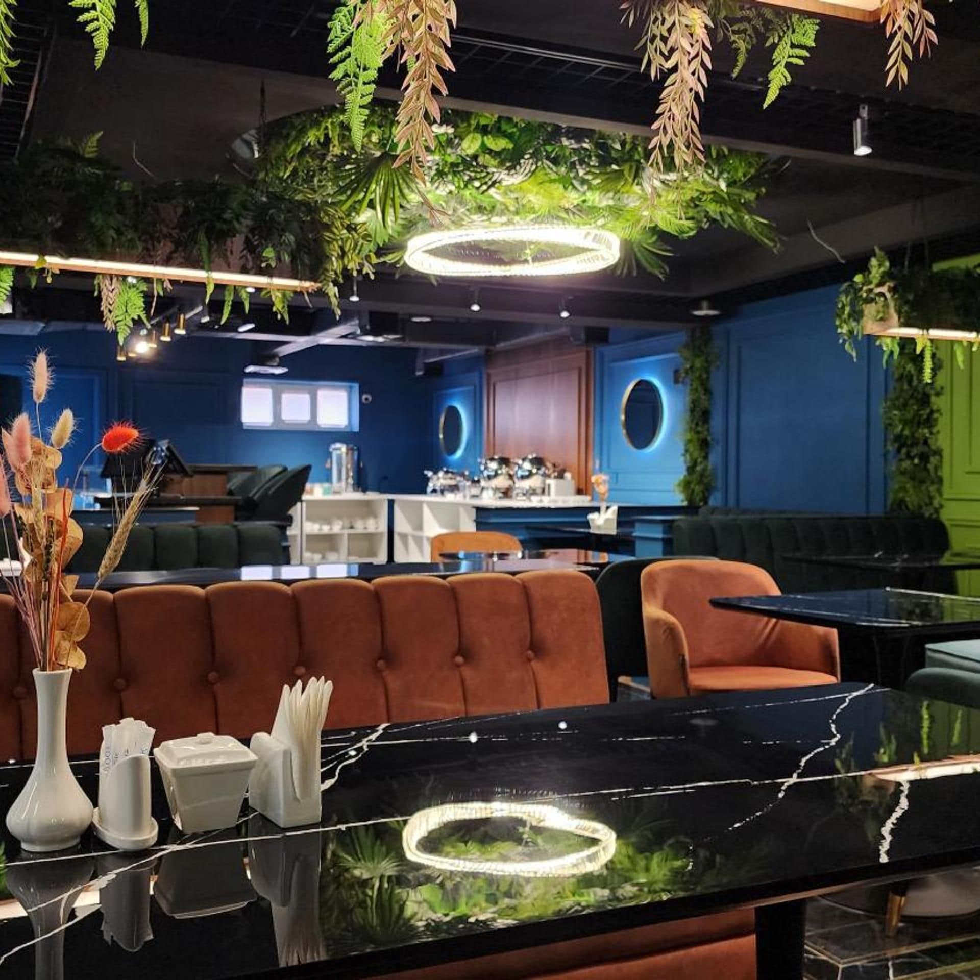 A modern interior with a bar area, seating, and hanging plants.