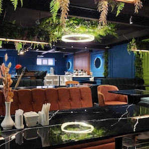 Een modern interieur met een bar, zitplaatsen en hangende planten.