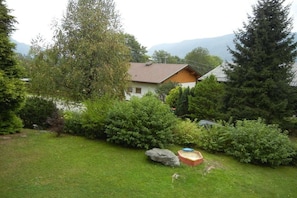 Ein Haus mit einem geneigten Dach, umgeben von dichtem Grün und Bäumen.