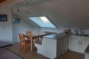 A compact kitchen with a skylight, wooden dining table, and white cabinetry. - Holiday apartment with 1 bedroom (Bodensdorf)