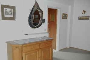 Ein Zimmer mit einem Holzkabinett, einem gerahmten Bild und einem Spiegel an der Wand.