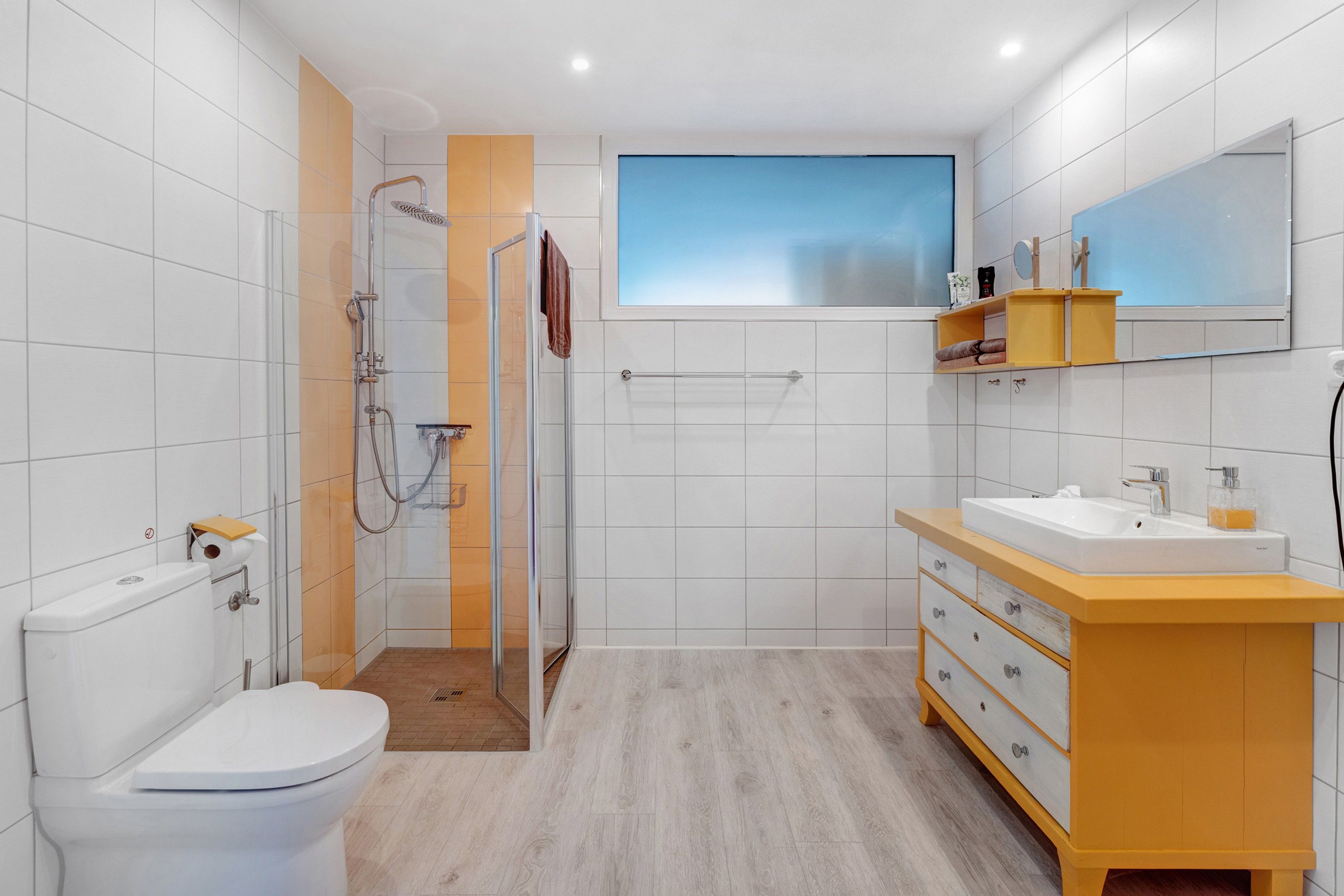 A modern bathroom with a toilet, shower, and vanity.