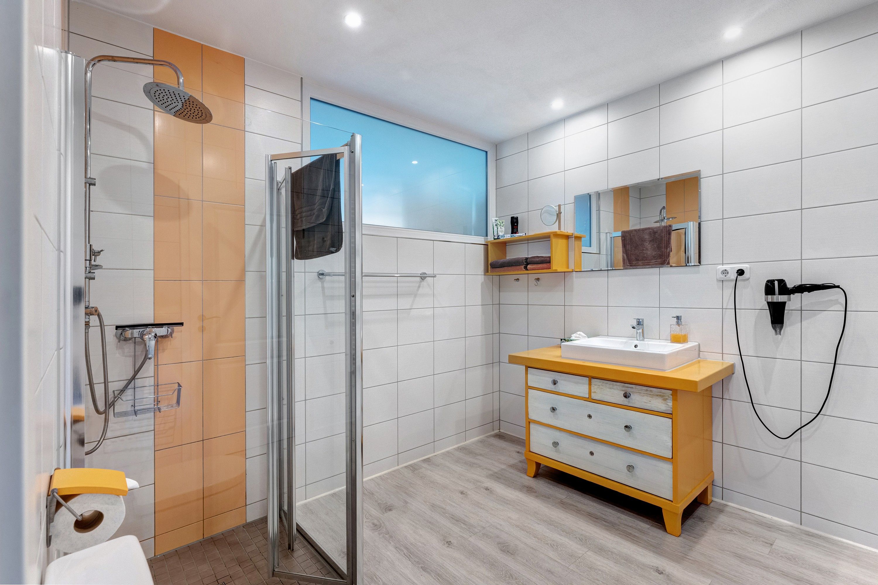 Ein modernes Badezimmer mit einer Duschkabine aus Glas, einem Holzbadezimmer-Möbelstück mit Spiegel und einer Toilette.