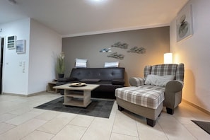 Ein modernes Wohnzimmer mit einer Couch, einem Sessel, einem Couchtisch und Wanddekoration.