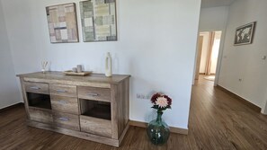 A room with a wooden dresser, a vase with flowers, and two abstract paintings on the wall. - Alma del Olivar Holiday Home (La Puebla de Cazalla)