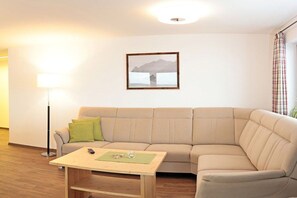 A living room with a beige sofa, a small wooden table, a floor lamp, and a framed picture on the wall. - Holiday apartment in Mittelberg with Wi-Fi (Mittelberg)