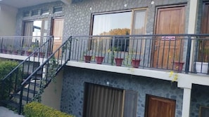 Un edificio de varios pisos con balcones, plantas en macetas y una escalera.