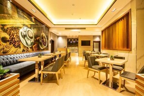 A restaurant with a modern interior, featuring a long counter with seating, a mural on the wall, and a wooden panel design on the back wall. - Wow Diamond Hotel (Jeddah)