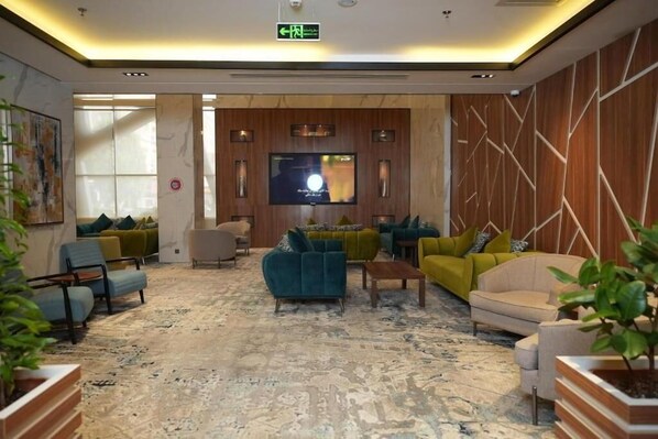 A lobby with a flat-screen TV, multiple sofas, and a patterned carpet. - Wow Diamond Hotel (Jeddah)