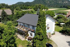 Ein Wohnhaus mit zweigeschossigem Haus, überdachter Terrasse und einem Garten mit Topfpflanzen.