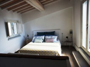 Ein Schlafzimmer mit einem Bett, einem Nachttisch, einer Lampe und einem Fenster.