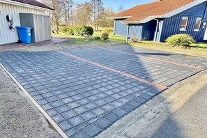 A paved driveway leading to a building with a blue exterior and a red roof. - Fjord house by the lake (Otterndorf)