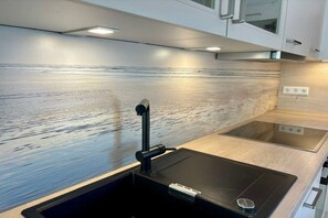 A modern kitchen with a built-in stove, a sink, and a countertop. - Fjord house by the lake (Otterndorf)