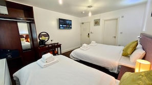 A hotel room with two beds, a desk with a computer, a TV, and a door. - Hotel Blackpool (Blackpool)