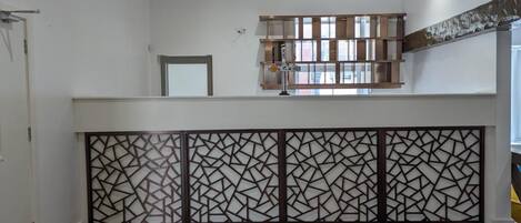 A modern interior with a wooden floor, a decorative partition, and a window with a view of buildings.