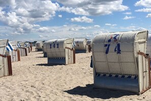 Strandliegen mit Nummern, auf einem Sandstrand aufgereiht.