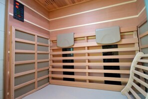 Een kamer met een wand van houten latten, een bedieningspaneel en een houten stoel.