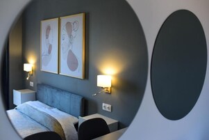 A hotel room with a bed, bedside tables, wall-mounted lamps, and abstract artwork.
