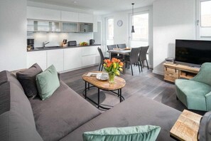 Ein stilvoller Wohnraum mit grauem Sofa, Couchtisch aus Holz und Flachbildfernseher.