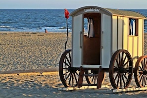 Eine Holzkonstruktion am Strand mit einem Schild, Rädern und einer Flagge.