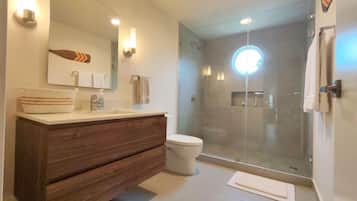 A modern bathroom with a wooden vanity, a glass shower enclosure, and a large mirror.